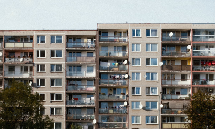 A block of beige flats with regular windows and crowded balconies.