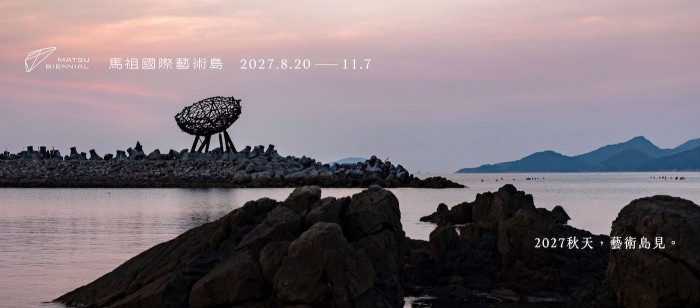 Title of the call on a photo of an artwork perched on rocks beside the sea. 