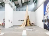 An exhibition space with tent-like shape and art on the walls. 