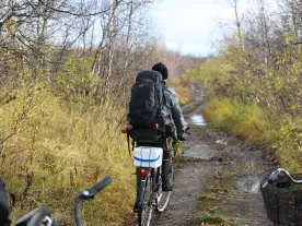 A person with a backpack on a bike on a dirt path.