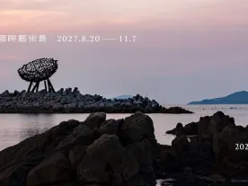 Title of the call on a photo of an artwork perched on rocks beside the sea. 