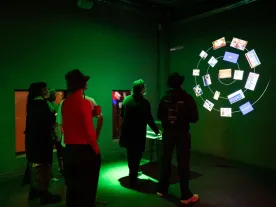 People in a green-lit room engaging with an installation. 