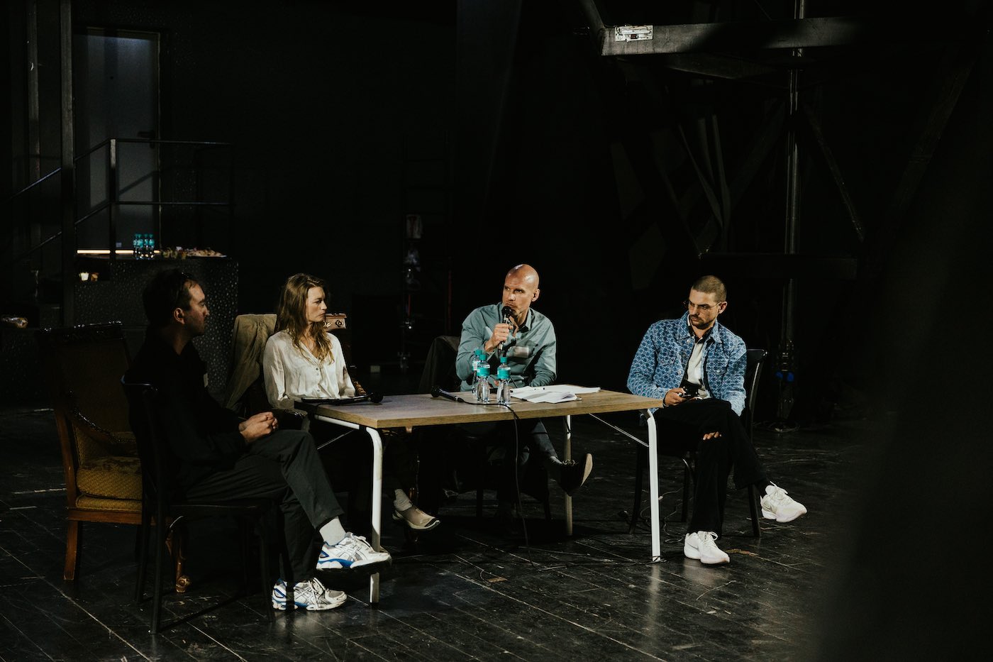 Four people sitting around a table, one of them talking into a mic.