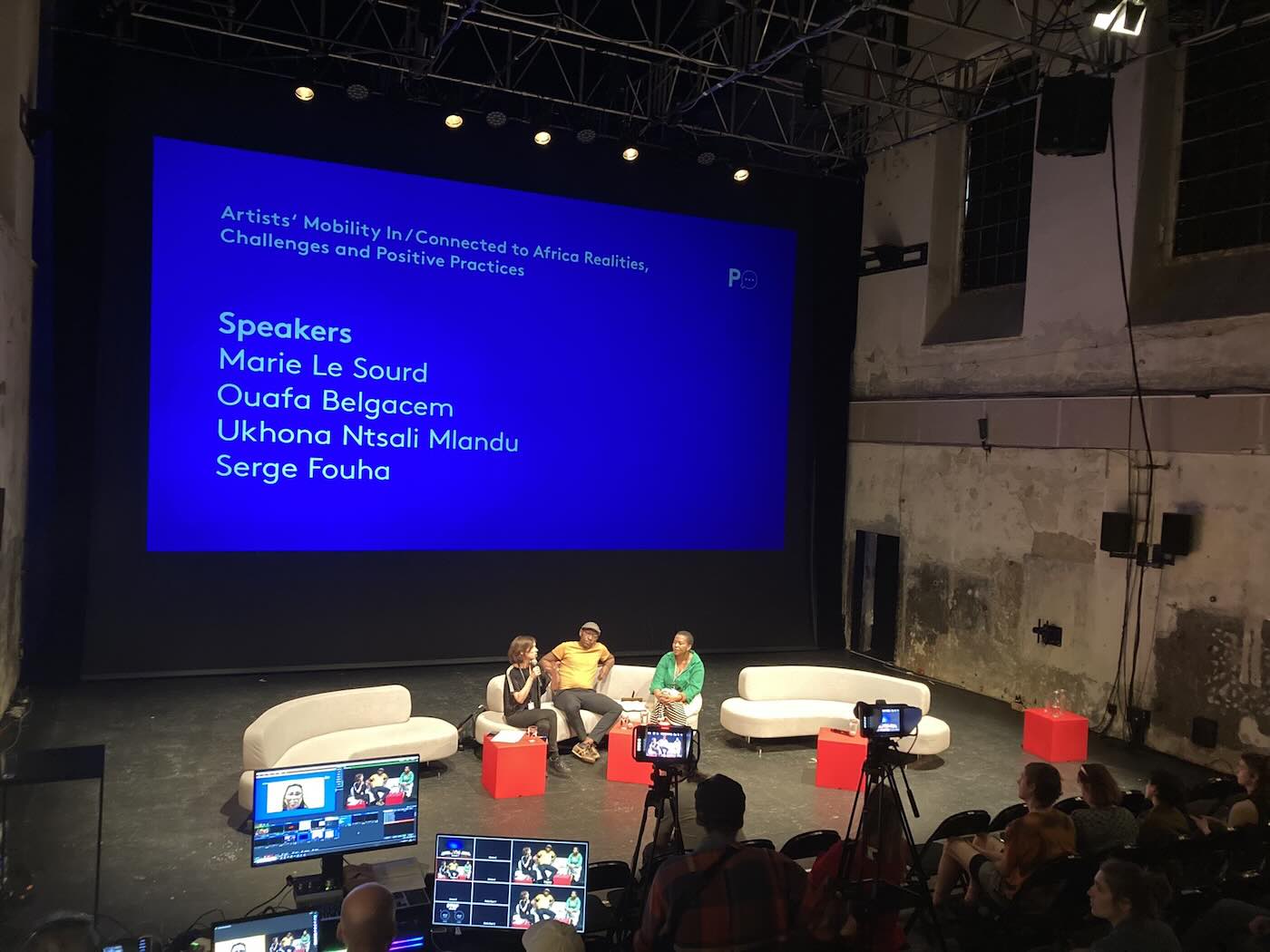 People talking on stage to a listening audience. 