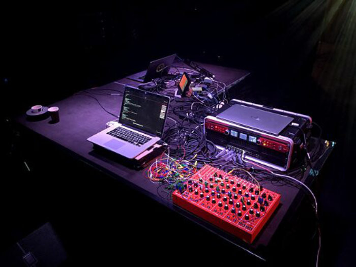 A complicated sound deck, with a thick tangle of wires connecting sound board, laptop and other components.