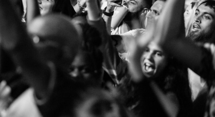 Black and white photo of a crowd of young people who look like they're at a festival or banging gig.