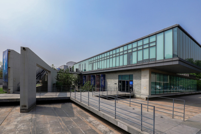 A modernist blocky glass building on a concrete plaza - OCAT Institute in Beijing.