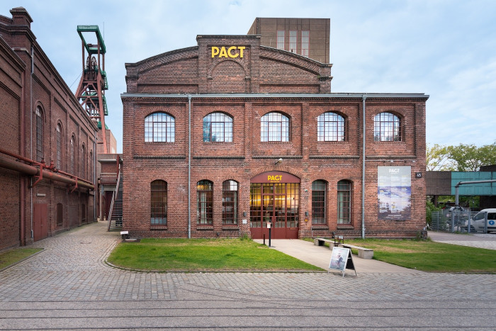 Brick factory building with 'PACT' written on the front. 