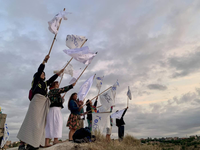 People standing on a raised space holding home-made flags aloft. 