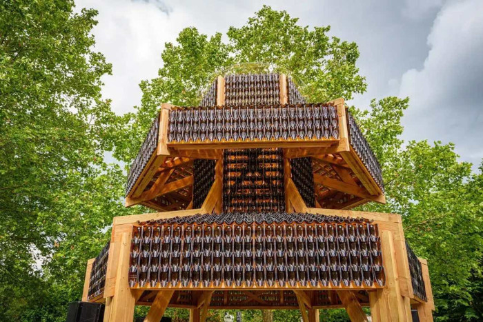A pagoda made out of bottles with trees behind. 