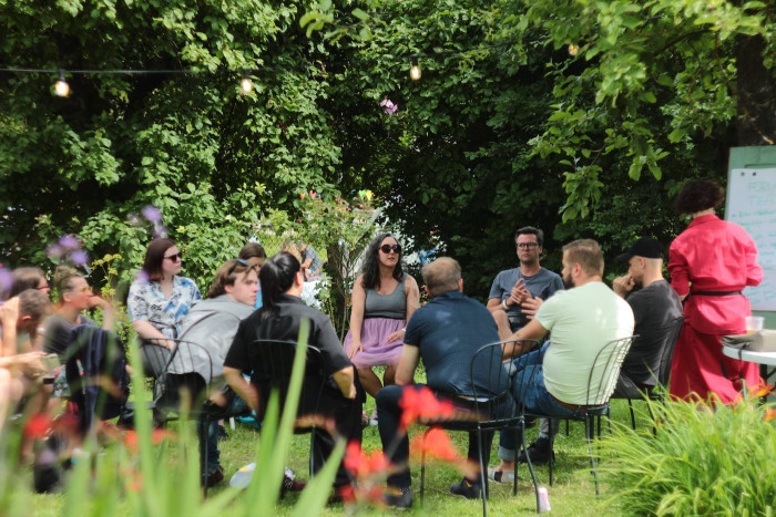 People talking in a circle in a garden setting. 