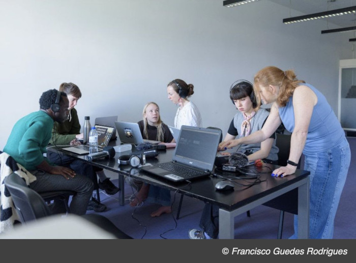 People around a table looking at computers and talking. 
