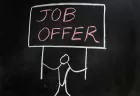 Chalk illustration of a stick man holding up a placard on which is written 'JOB OFFER'.