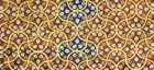 Flowing yellow lines form a lattice filled with small white and orange flowers in an arabesque pattern.