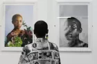 A woman looks at two portrait photographs in a gallery.