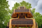 A pagoda made out of bottles with trees behind. 