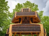 A pagoda made out of bottles with trees behind. 