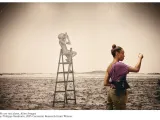 A person standing in front of a work on a wall. 