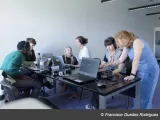 People around a table looking at computers and talking. 