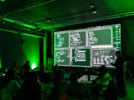 A room with a presentation screen, lit by green lights.