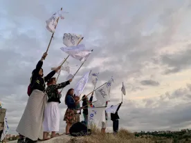 People standing on a raised space holding home-made flags aloft. 
