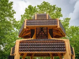 A pagoda made out of bottles with trees behind. 