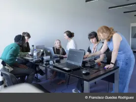 People around a table looking at computers and talking. 